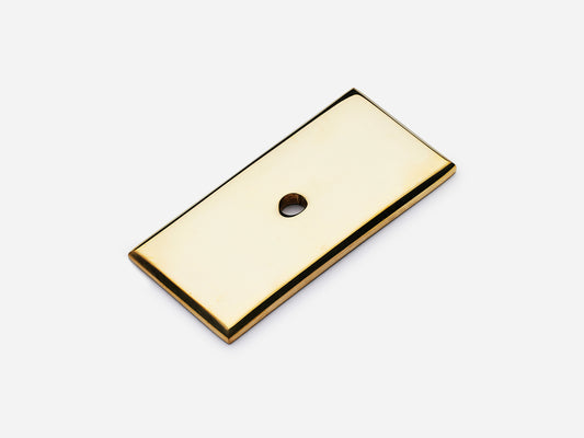 Solid brass rectangular backplate, 1x2 inches, unlacquered polished brass finish for knobs and pulls on cabinets.