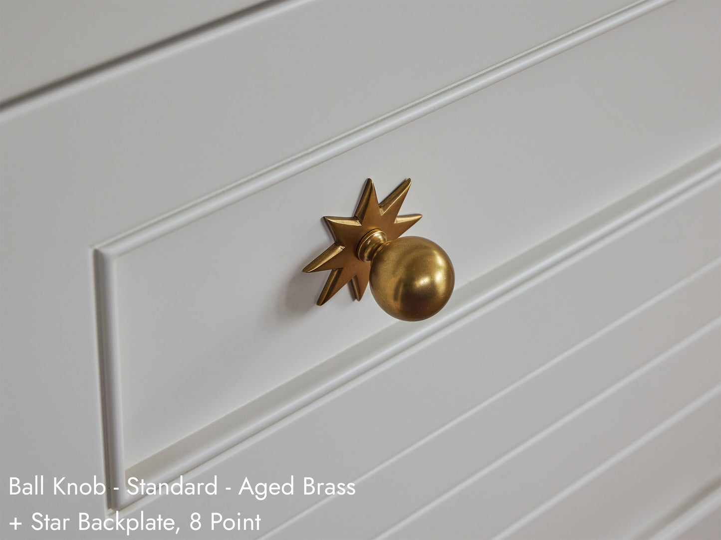 Solid brass Ball Knob with Star Backplate, in aged brass finish, on kitchen cabinets.