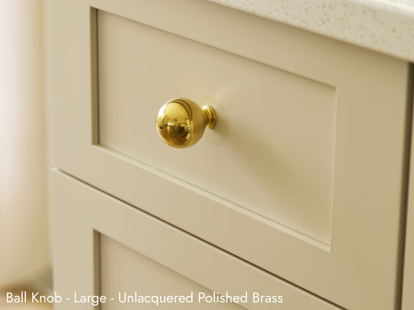 Solid brass Ball Knob, in unlacquered polished brass finish, on kitchen cabinets.