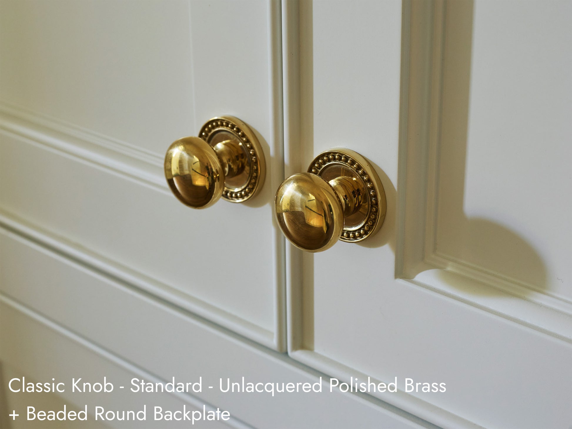 Solid brass Classic Knob, in unlacquered polished brass finish, on kitchen cabinets with Beaded Round Backplate.