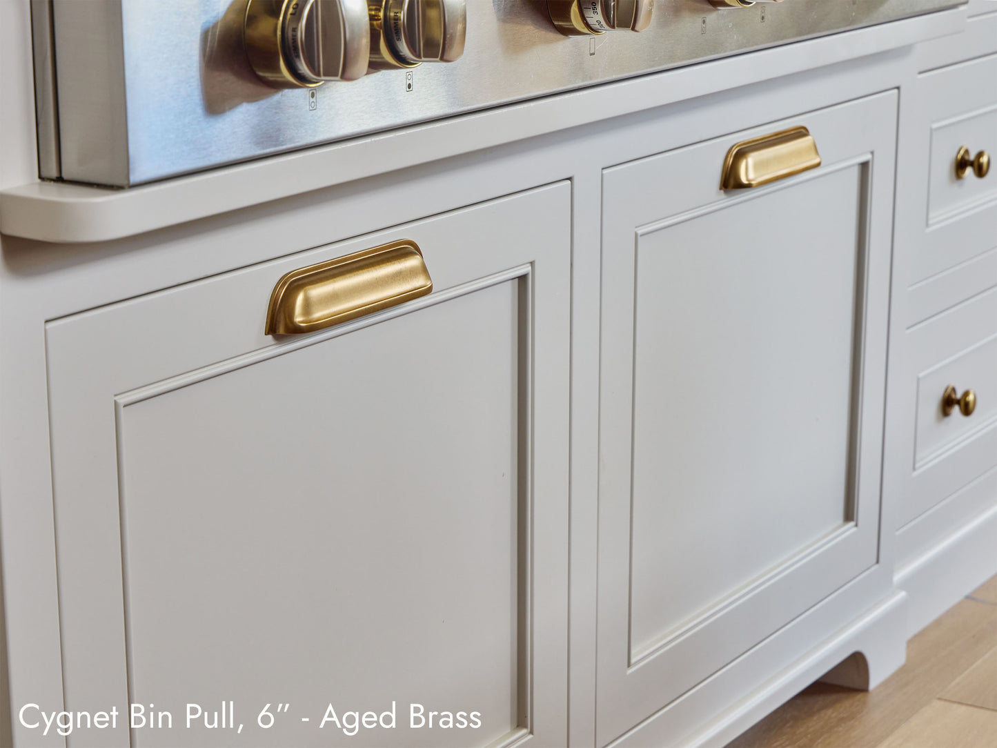 Solid brass Cygnet Bin Pull, in aged brass finish, on kitchen cabinets.