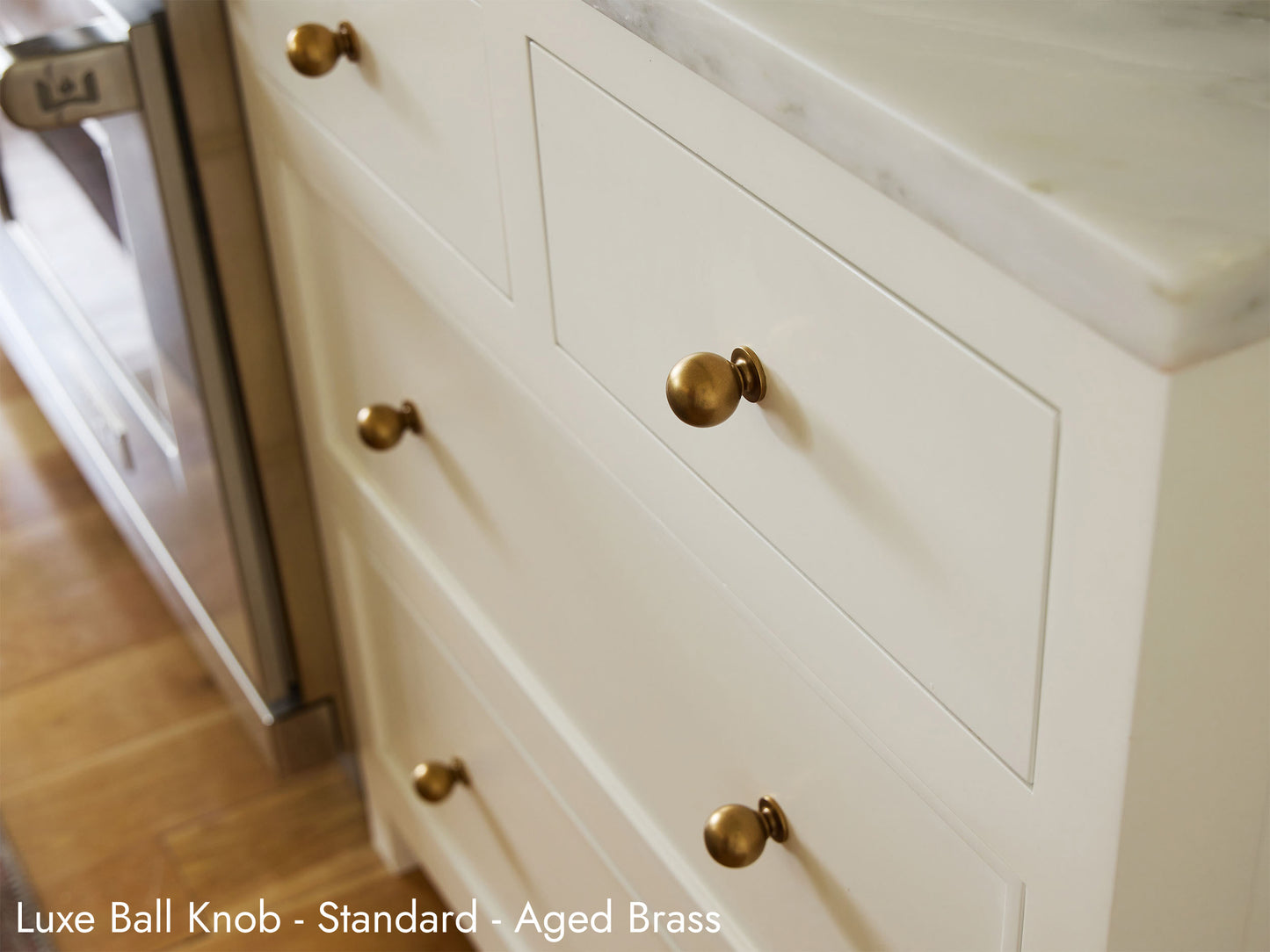 Solid brass Luxe Ball Knobs in Aged Brass finish on kitchen cabinets.