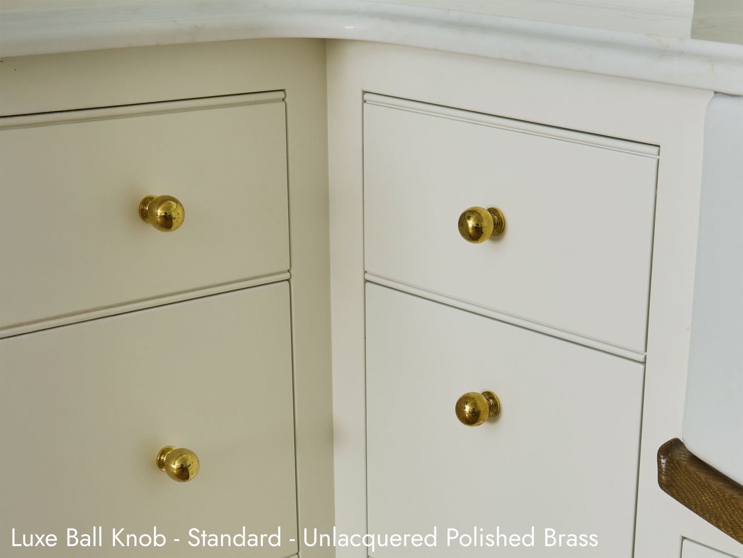 Solid brass Luxe Ball Knob, in unlacquered polished brass finish, on kitchen cabinets.