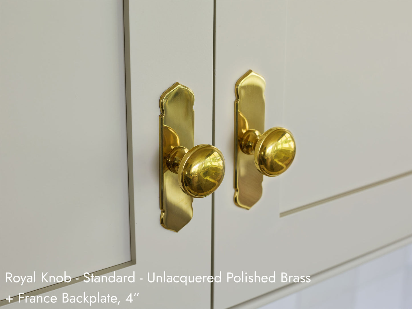 Solid brass Royal Knobs, in unlacquered polished brass finish, on kitchen cabinets with France Backplates.