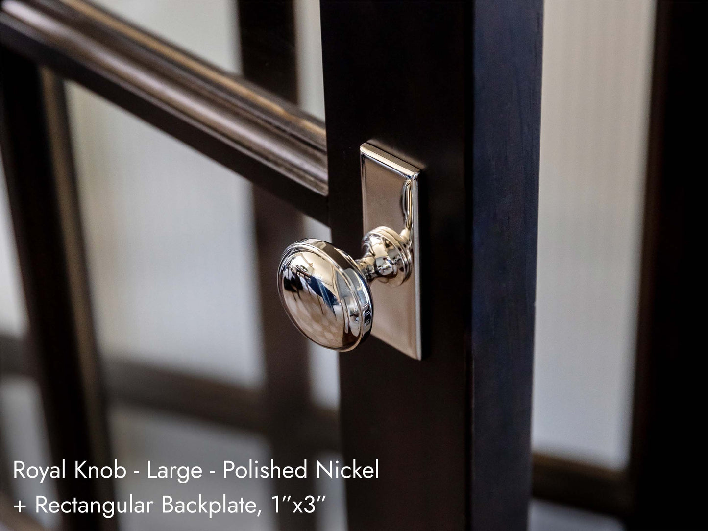 Solid brass Royal Knob, in polished nickel, with a backplate and mounted on a door.