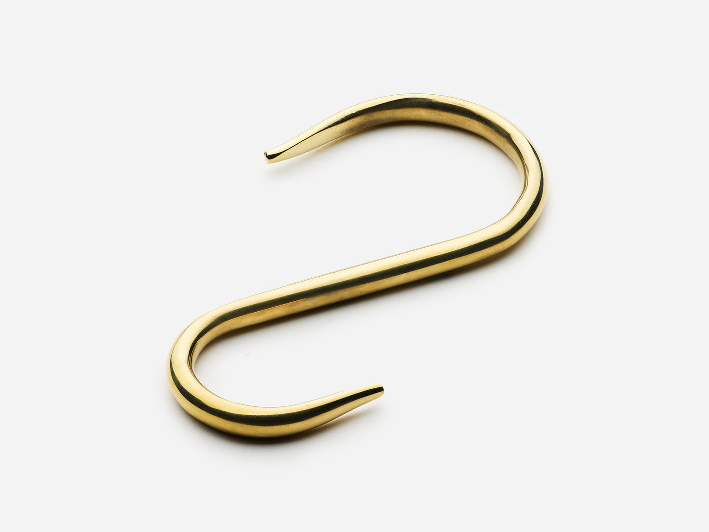 Solid brass S-hook for hanging pot rail in an unlacquered polished brass finish for kitchens.