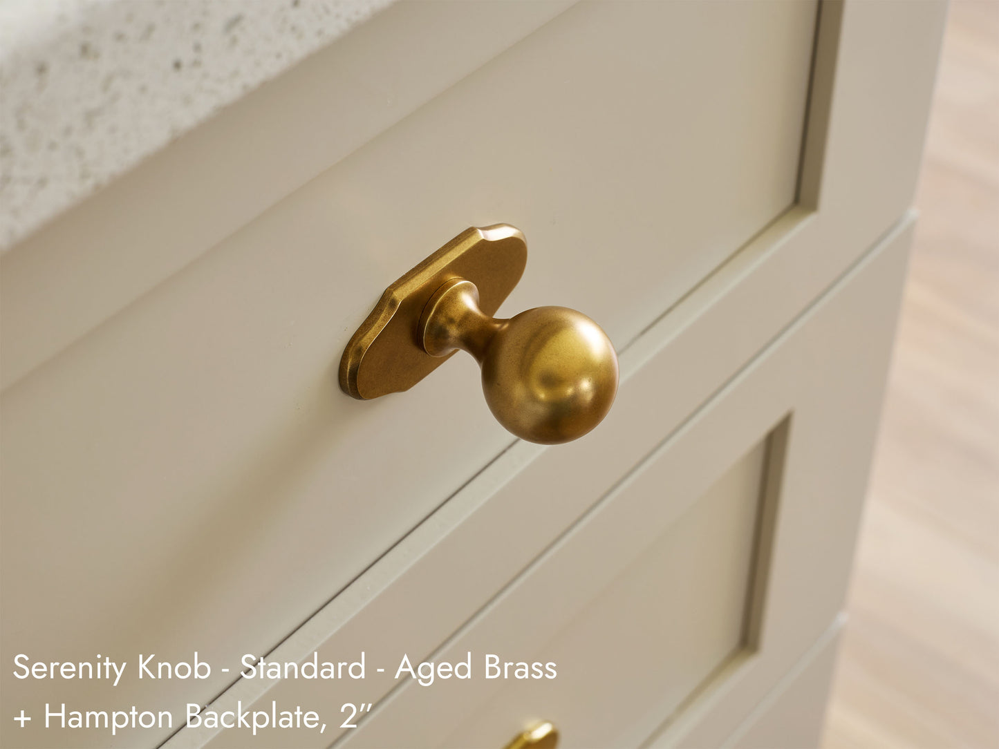 Solid brass Serenity Knob, in unlacquered polished brass finish, on kitchen cabinets with Hampton Backplate.