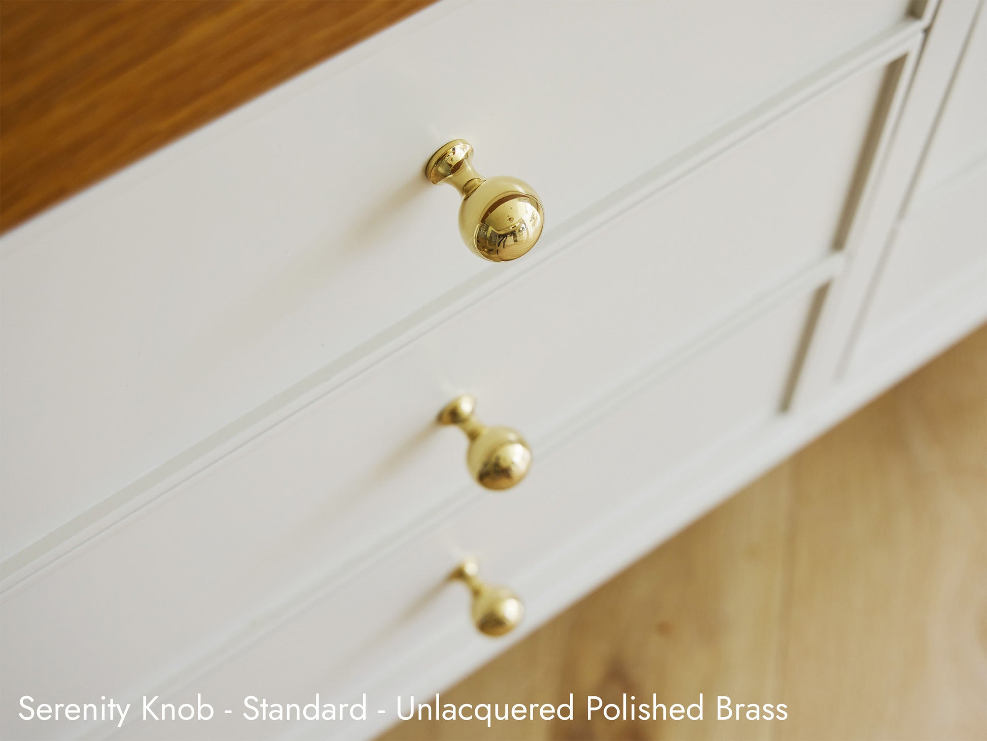 Solid brass Serenity Knob in unlacquered polished brass on kitchen cabinets.