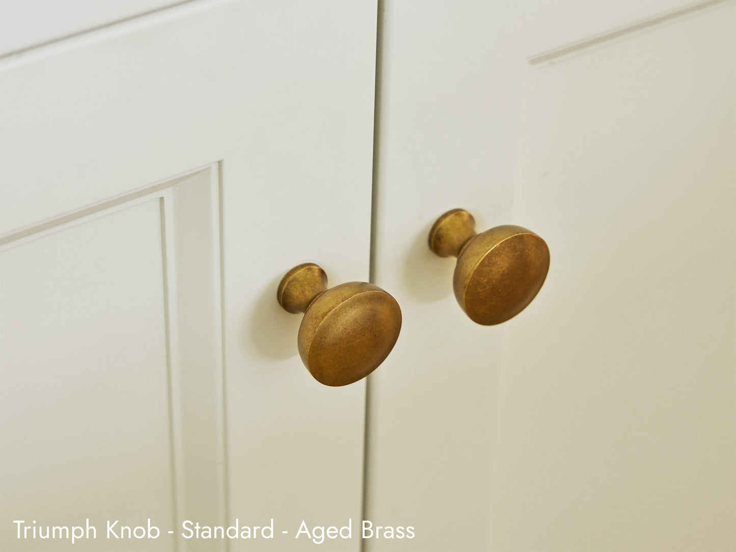 Solid brass Triumph Knob in aged brass on kitchen cabinets.