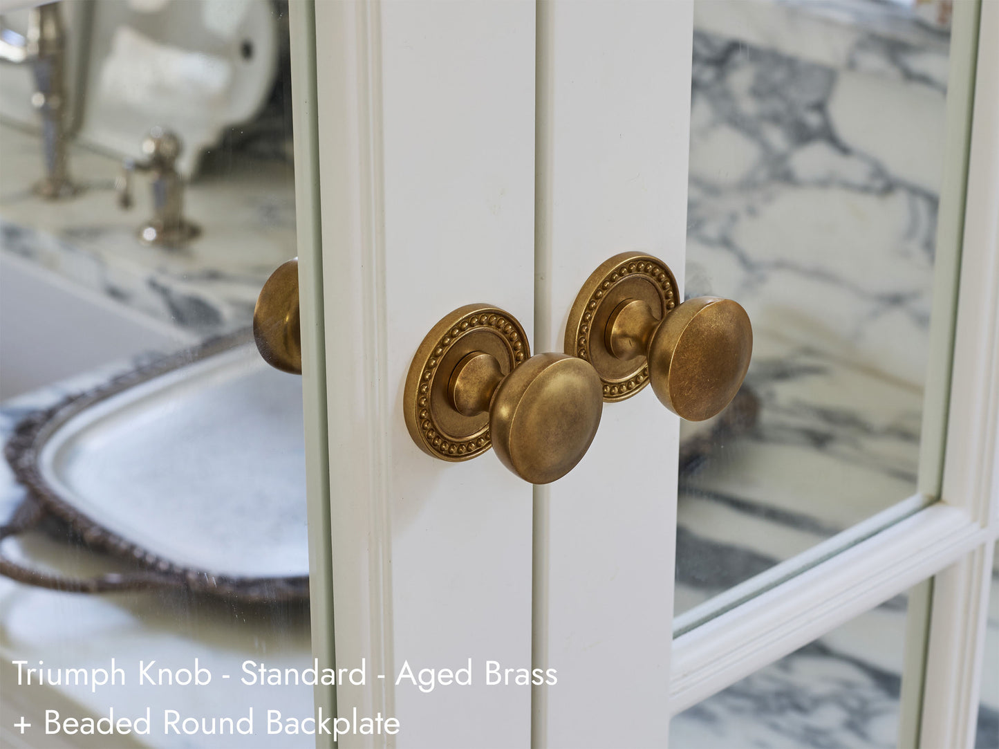 Solid brass Triumph Knob in aged brass on kitchen cabinets.