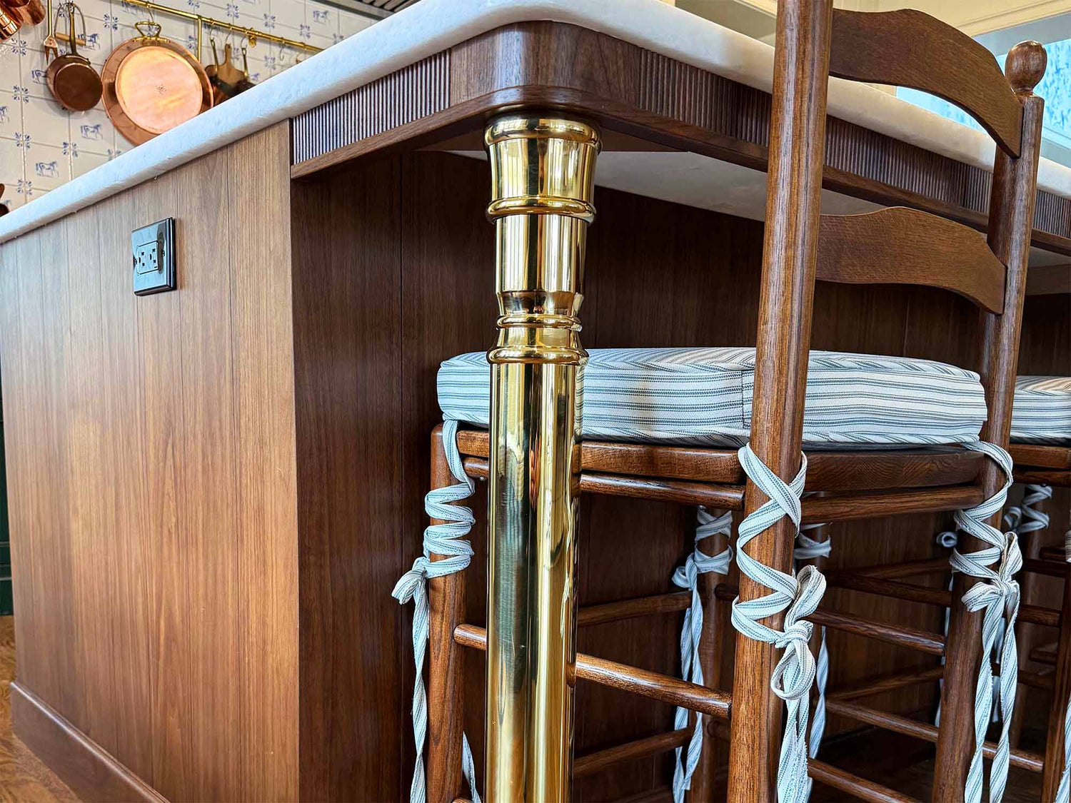 A solid brass kitchen island leg, with an unlacquered polished brass finish, installed on a wood kitchen island in a traditional styled kitchen.