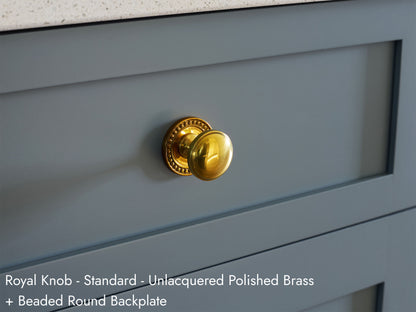 Solid brass Royal Knob, in unlacquered polished brass finish, on kitchen cabinets with Beaded Round Backplate.